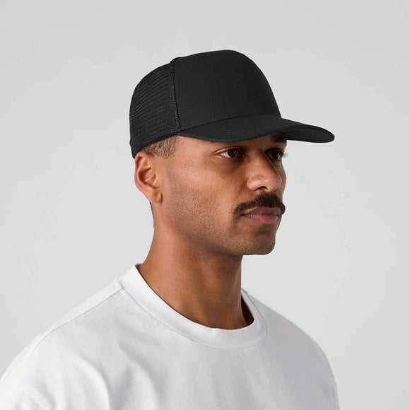 Man wearing a black cap and white shirt against a gray background