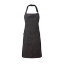 A black bib-apron with a leather-like adjustable strap at the neck and a pen pocket on the front. It is displayed against a white background. Premier Annex Oxford Bib Apron - PR144