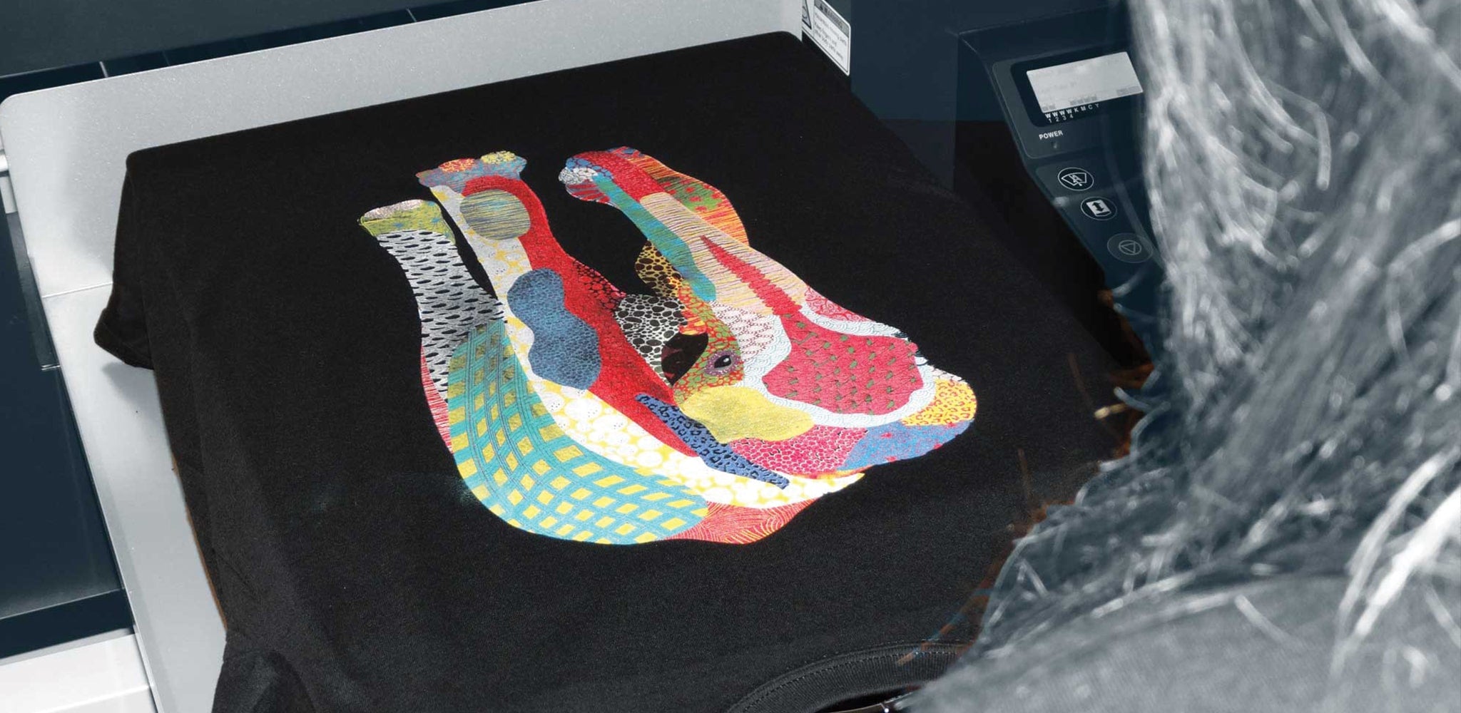 A black t-shirt laid on a platen with a mulit-coloured elephant printed on the front.