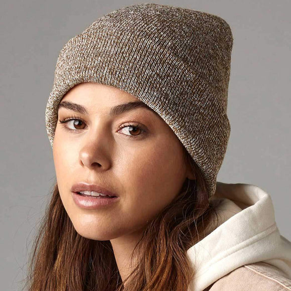 Woman wearing a beige knit beanie against a gray background