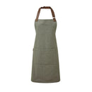 A moss green bib-apron with a pen pocket and brown straps, made of cotton fabric. It is displayed against a white background Premier Annex Oxford Bib Apron - PR144