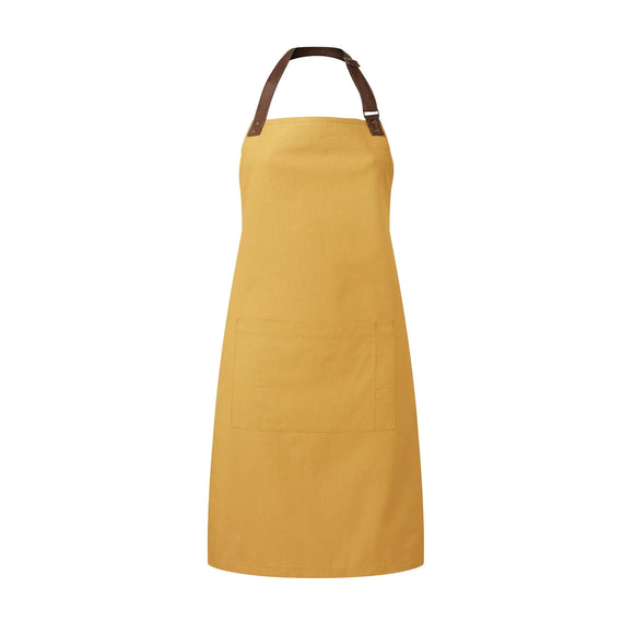 A mustard yellow bib-apron with a leather-like adjustable strap at the neck and a pen pocket on the front. It is displayed against a white background. Premier Annex Oxford Bib Apron - PR144