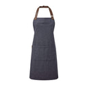 A navy blue bib-apron with a leather-like adjustable strap at the neck and a pen pocket on the front. It is displayed against a white  background. Premier Annex Oxford Bib Apron - PR144