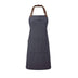 A navy blue bib-apron with a leather-like adjustable strap at the neck and a pen pocket on the front. It is displayed against a white  background. Premier Annex Oxford Bib Apron - PR144