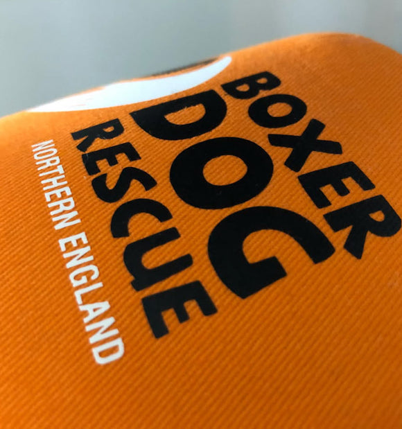 Close-up of an orange fabric item printed with large black text reading 'BOXER DOG' and smaller white text reading 'NORTHERN ENGLAND'.