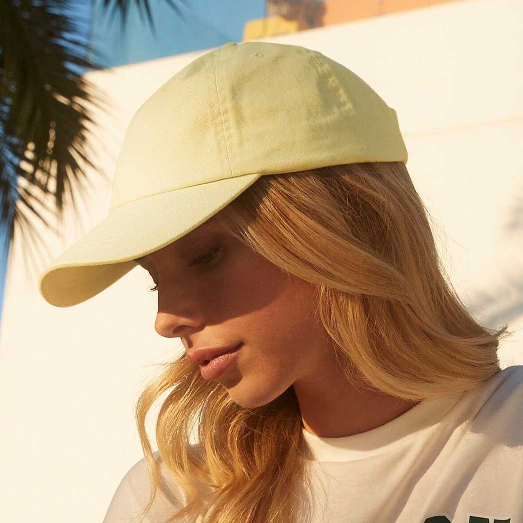 Person wearing a light yellow cap with palm leaves in the background