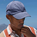 Man wearing a blue cap and striped shirt against a clear blue sky