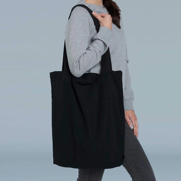 Person wearing a black tote bag on a plain background