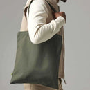 Person holding a green tote bag against a plain background