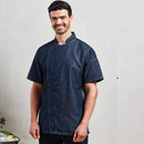 A model wearing a short sleeve indigo denim chef's jacket with a mandarin collar, side vents, and a zip-close front. Premier Chef's Zip-Close Short Sleeve Jacket - PR906