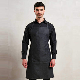Man wearing a black shirt with a blue denim Bib Apron with Pocket on a light grey background. Denim Bib Apron with Pocket - PR154